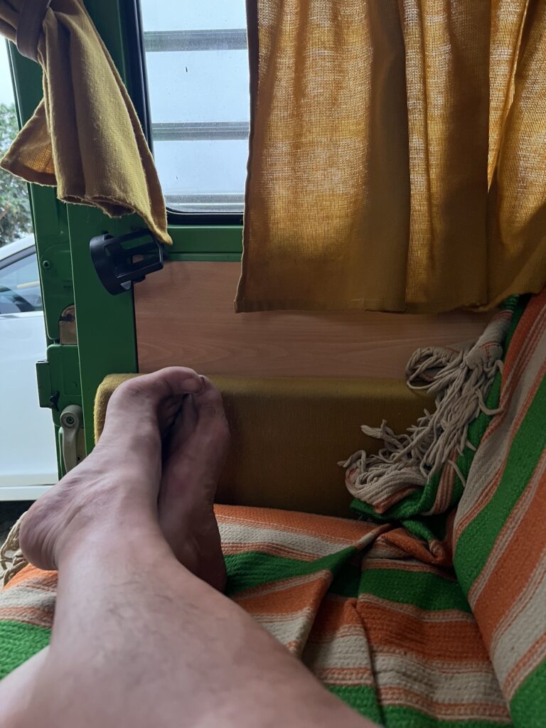 Piernas estiradas sobre una manta de rayas dentro de la combi